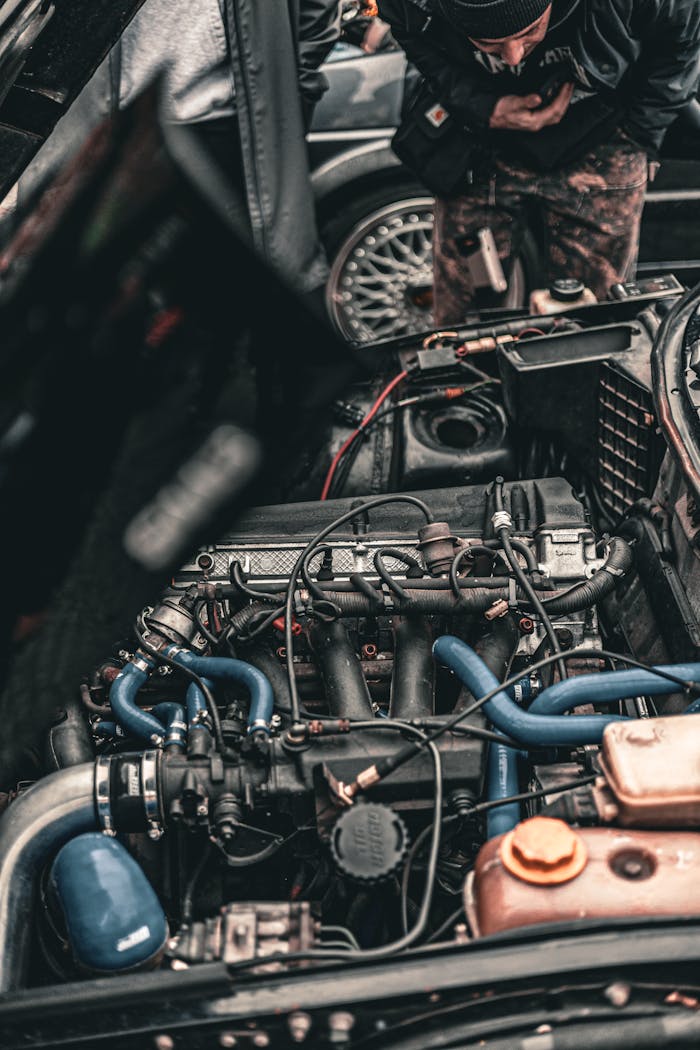 Close-up image of a car engine with a mechanic inspecting it, showcasing automotive engineering details.