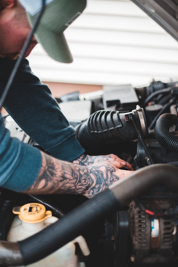 Side view of crop male technician in cap concentrating during car engine repair