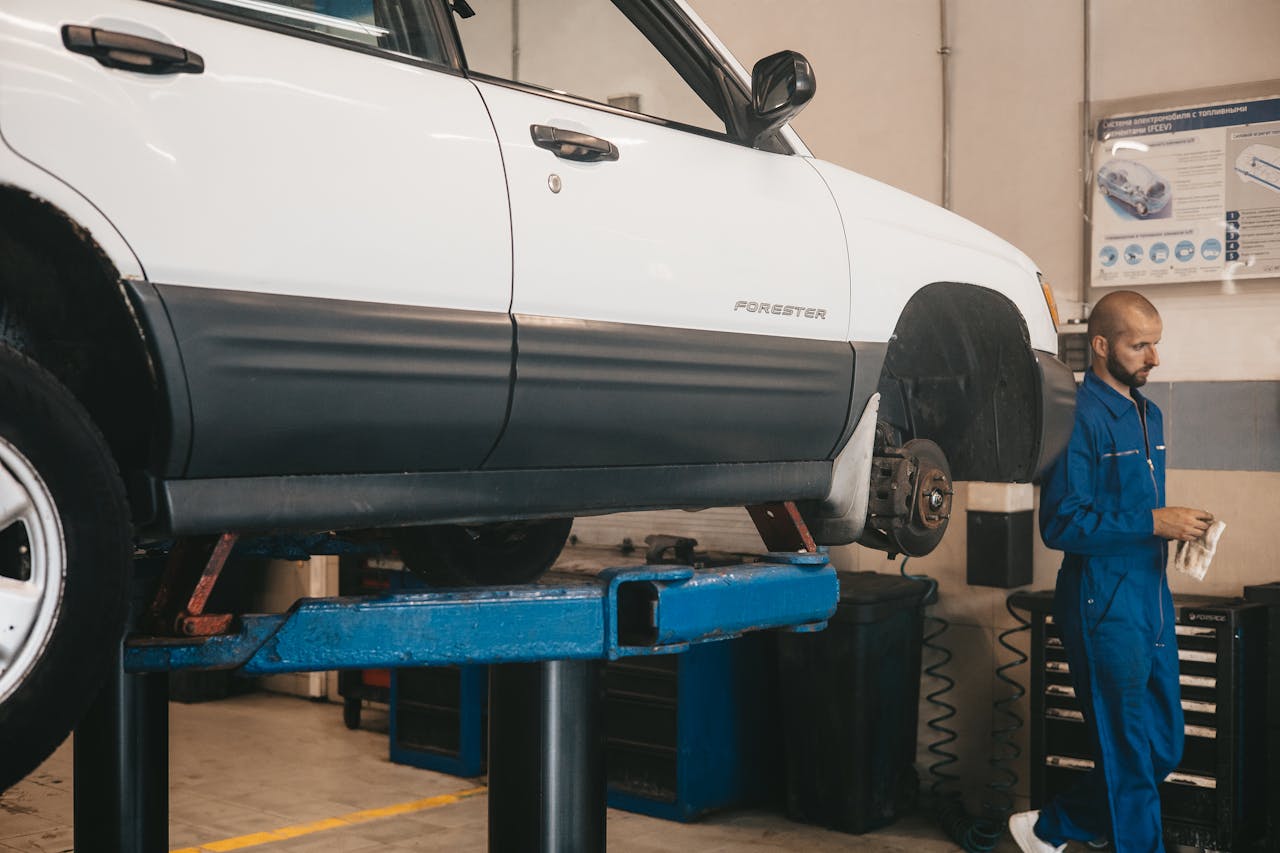Mechanic evaluating a car on a lift for maintenance in an auto workshop.